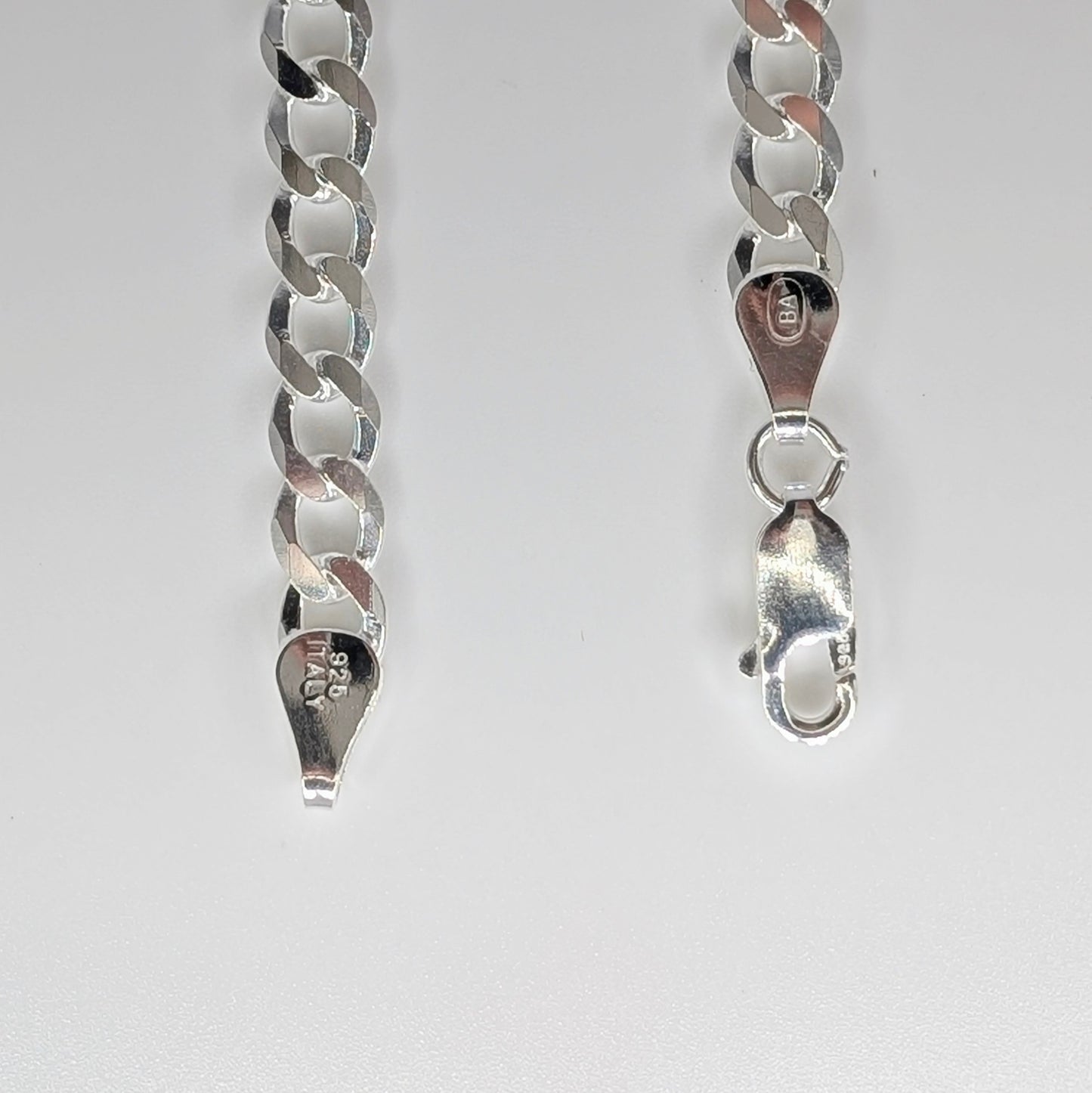 Silver chain necklace showing the curb link style, a lobster clasp closure, and a sterling silver hallmark.