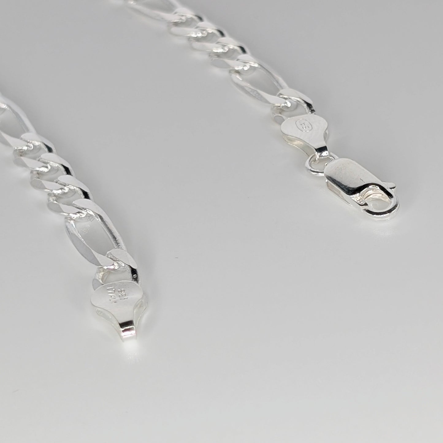 A close-up of a polished silver chain necklace with elongated links and lobster clasp ends.