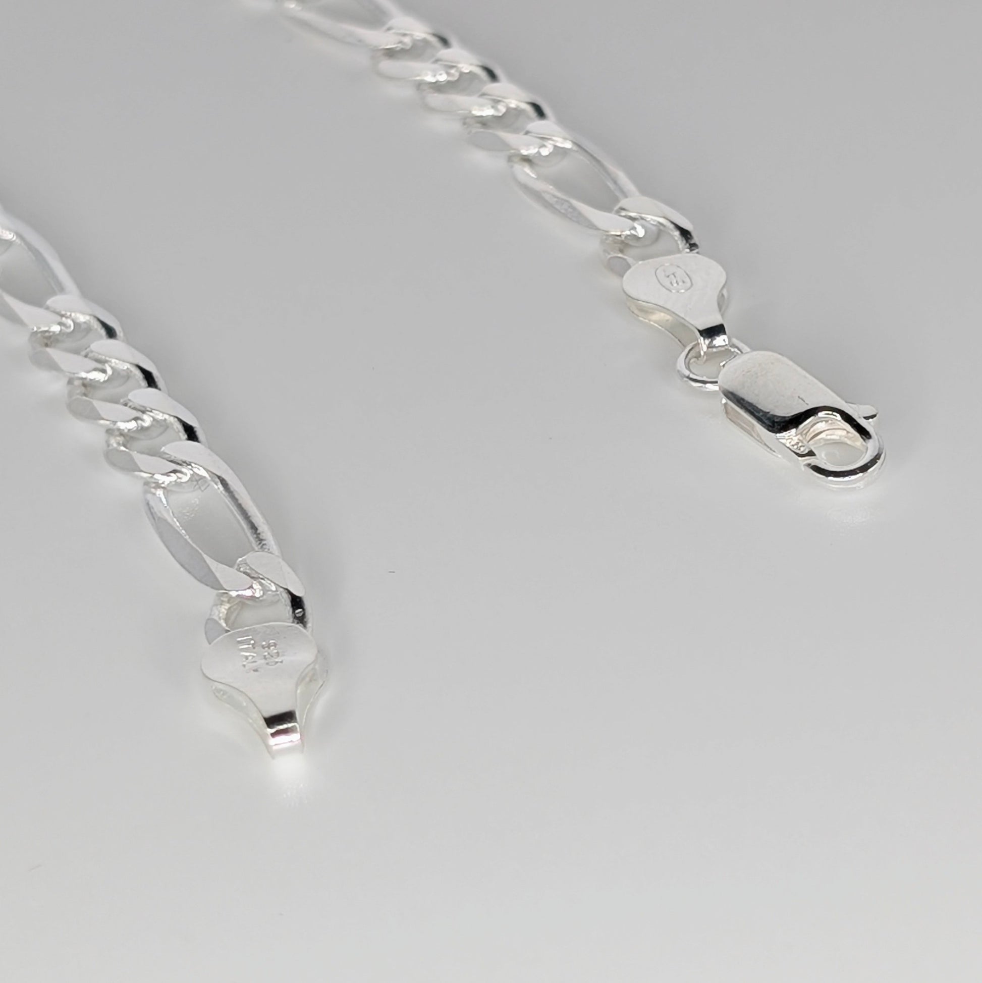 A close-up of a polished silver chain necklace with elongated links and lobster clasp ends.