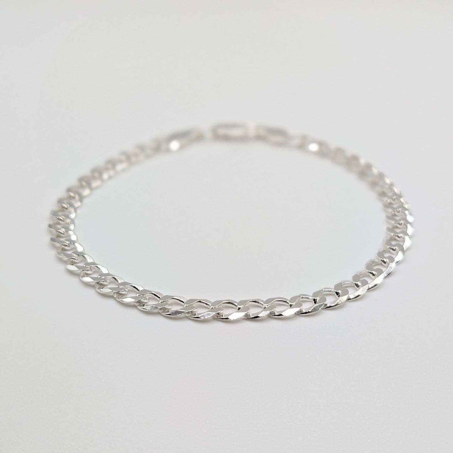 A sterling silver chain bracelet with a curb link design.