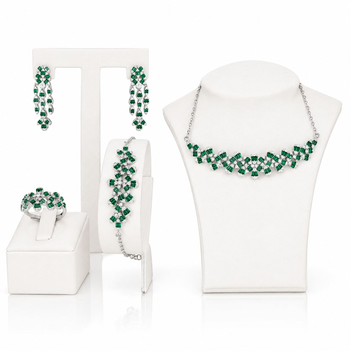 A coordinated jewelry set displayed on white mannequin stands and a surface, including a necklace, earrings, bracelet, and ring. The pieces feature bright green faceted stones set in sterling silver.