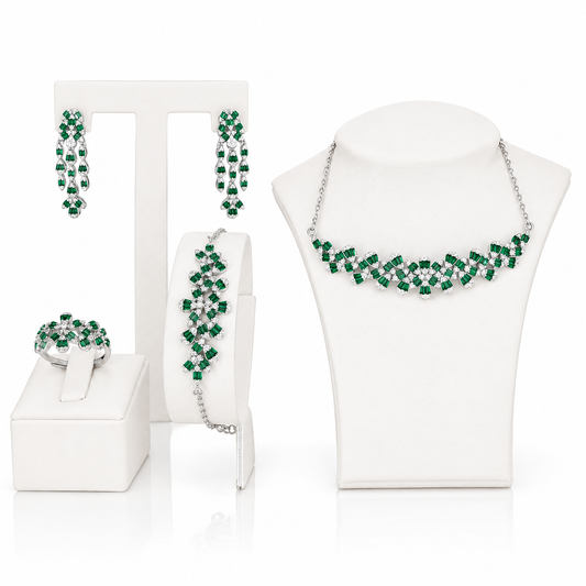 A coordinated jewelry set displayed on white mannequin stands and a surface, including a necklace, earrings, bracelet, and ring. The pieces feature bright green faceted stones set in sterling silver.