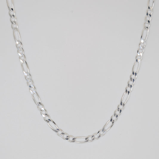 A silver Figaro chain necklace with alternating oval and elongated links, displayed in a U-shape against a neutral light gray background.
