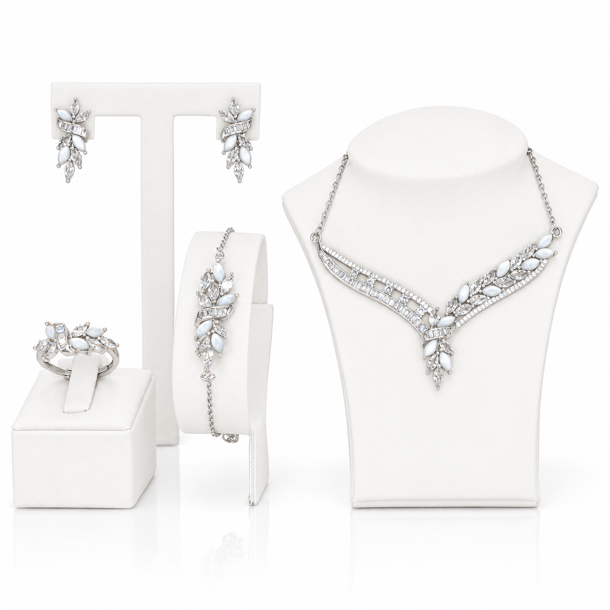 A coordinated jewelry set displayed on white mannequin stands and a stand: a sterling silver necklace with clear marquise and round stones, matching earrings, a bracelet, and a ring.