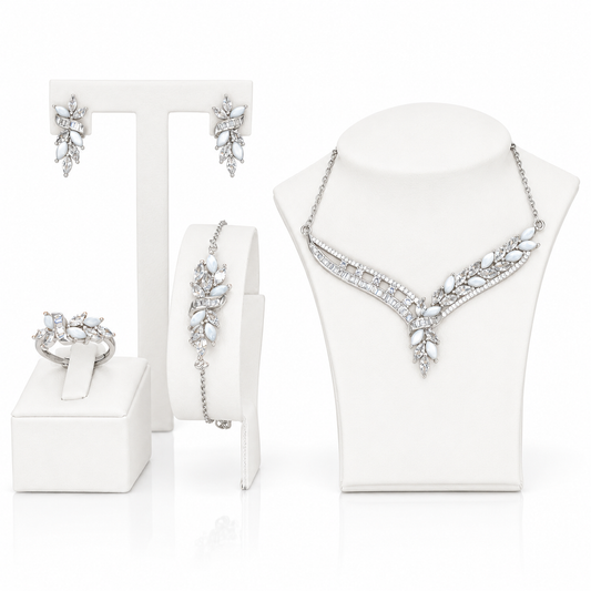 A coordinated jewelry set displayed on white mannequin stands and a stand: a sterling silver necklace with clear marquise and round stones, matching earrings, a bracelet, and a ring.
