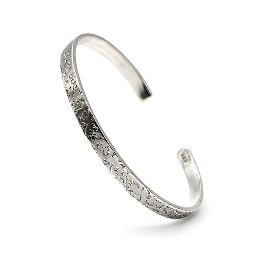 A polished silver cuff bracelet with a textured, hammered floral pattern on the outer surface.