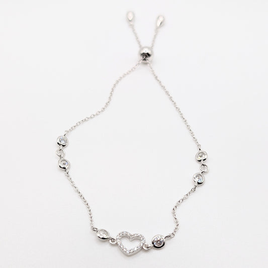 A delicate silver chain bracelet with a heart-shaped charm and small silver beads.