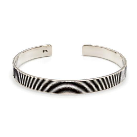 A sterling silver cuff bracelet with a textured, ridged exterior and a polished interior.