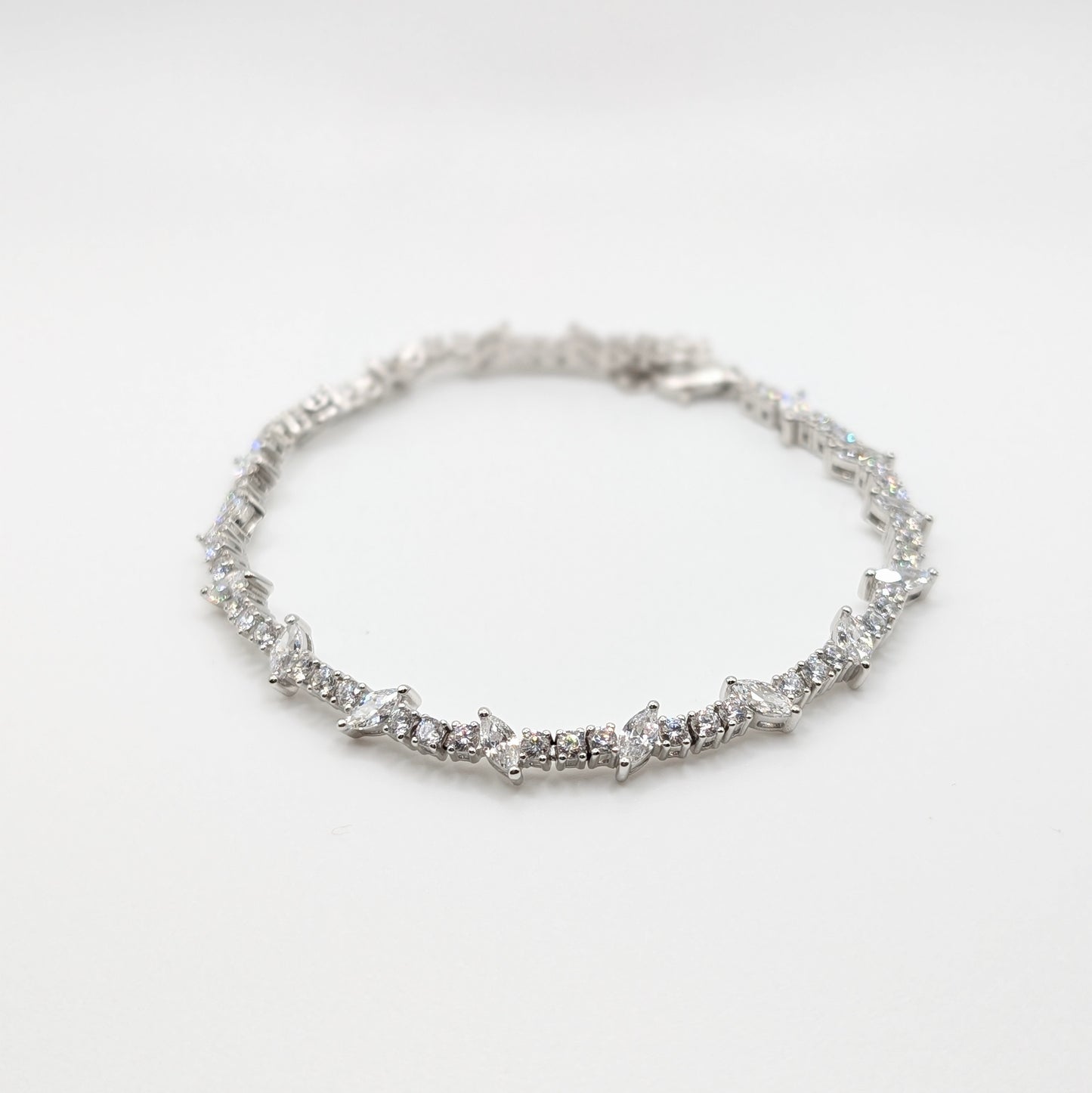 A silver tennis bracelet with a continuous line of small sparkling stones.