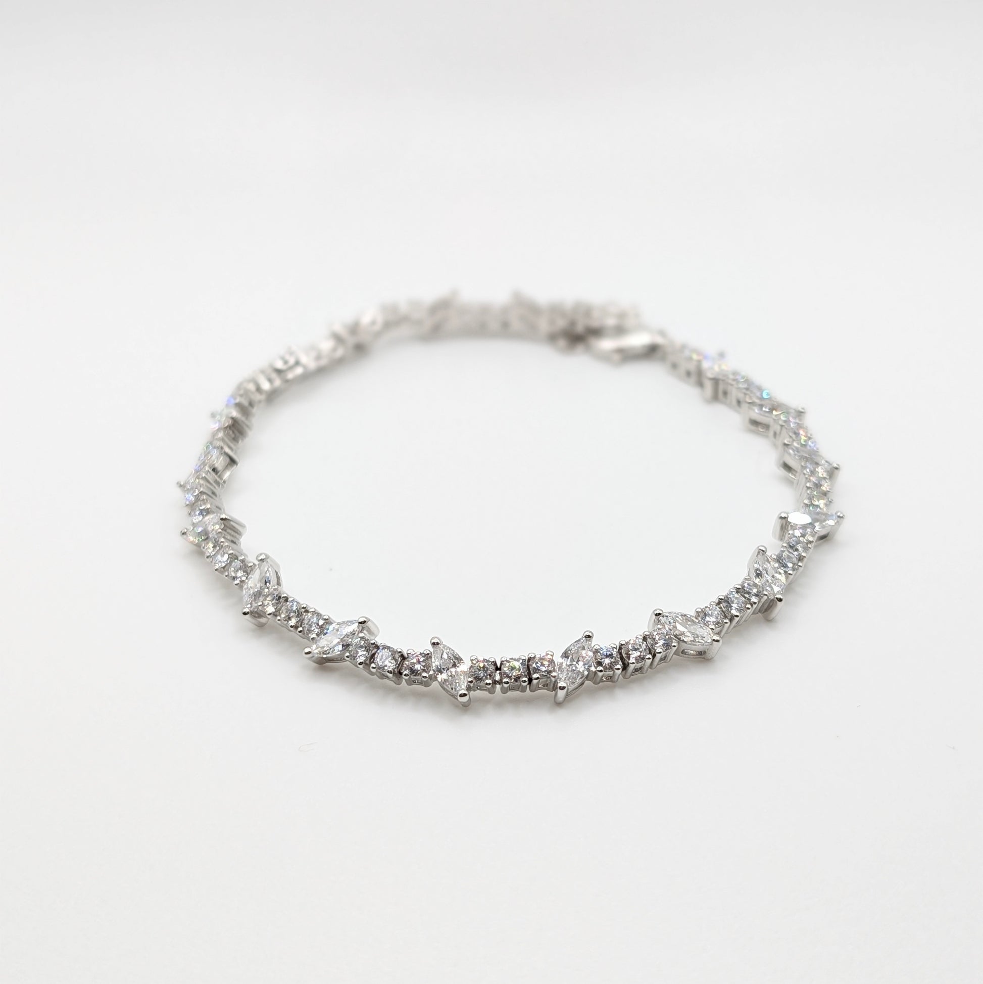 A silver tennis bracelet with a continuous line of small sparkling stones.