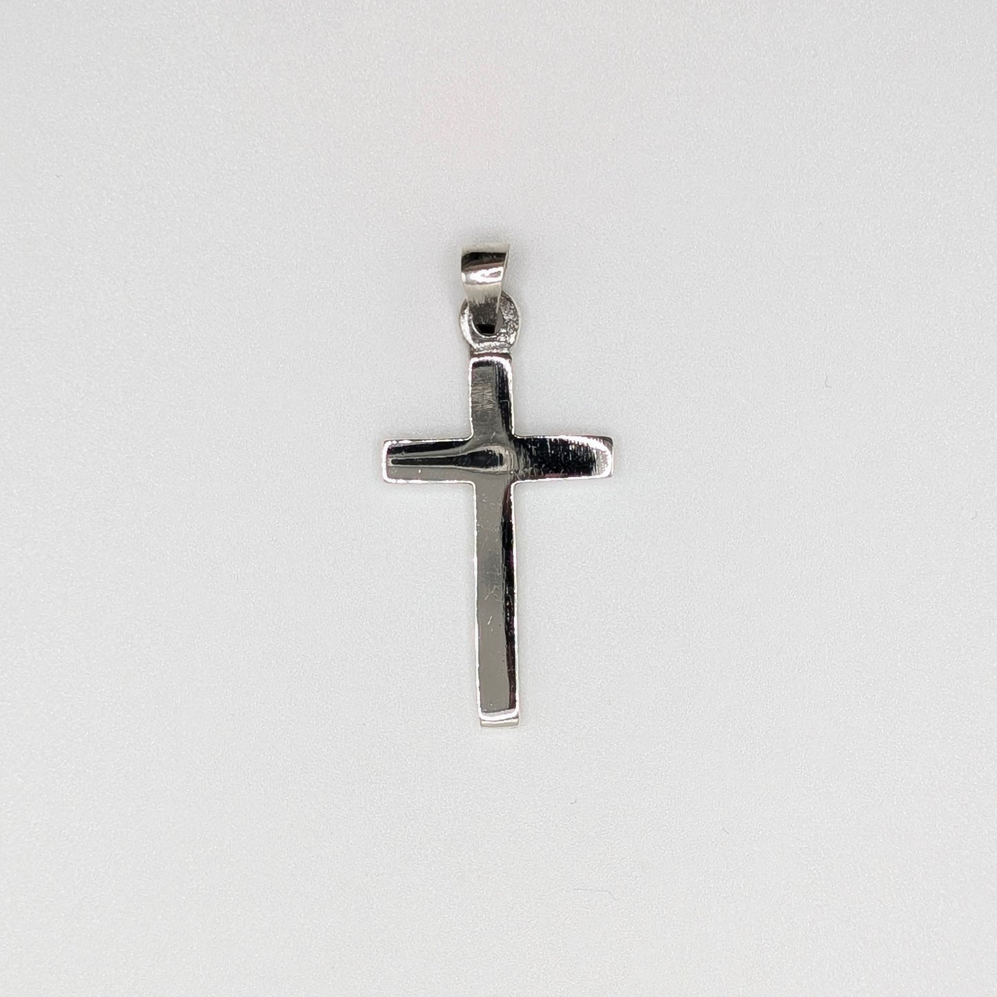 A polished silver cross pendant with a flat, textured surface and a top bail.